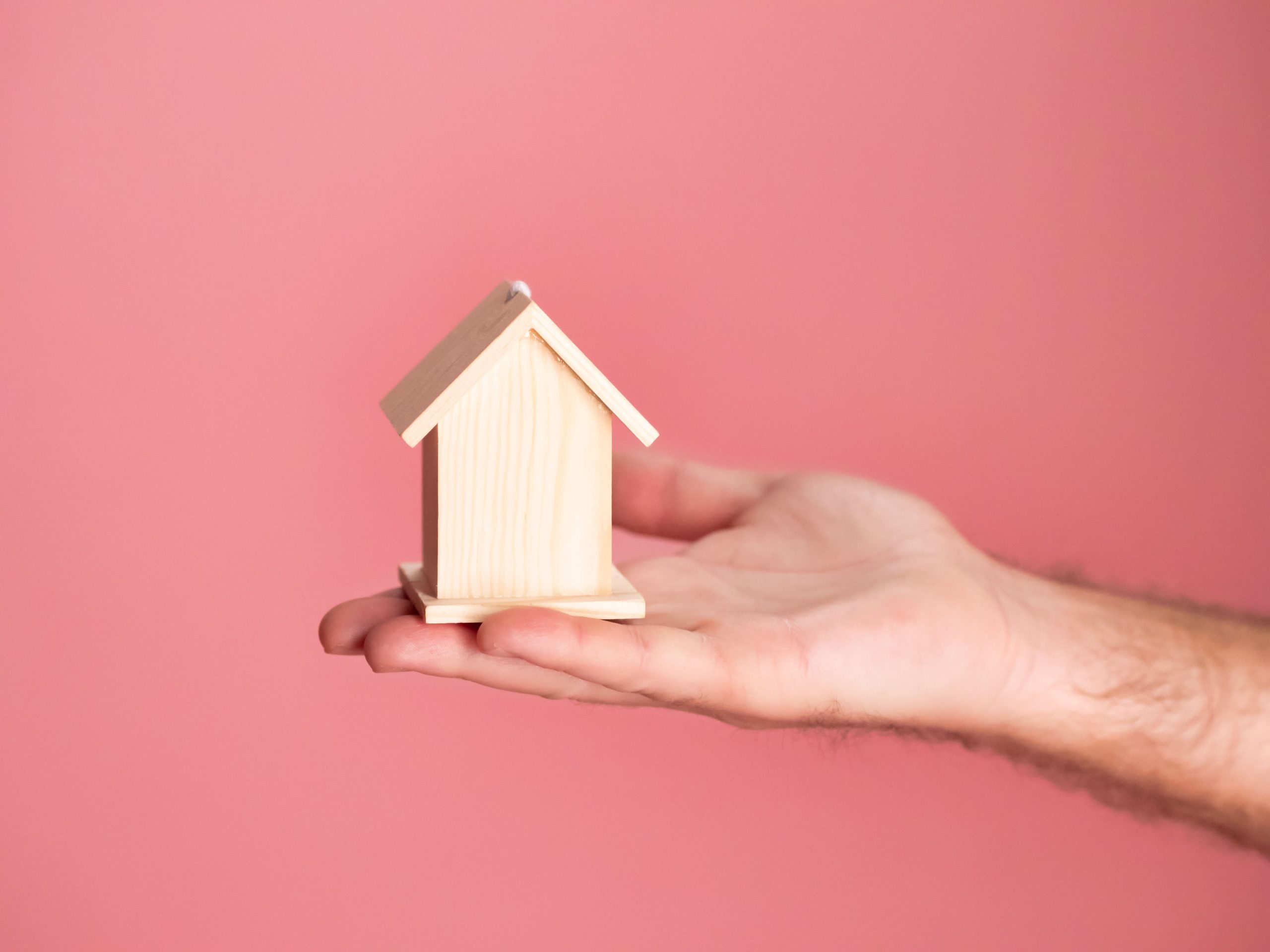 Main tenant maquette maison sur fond rose