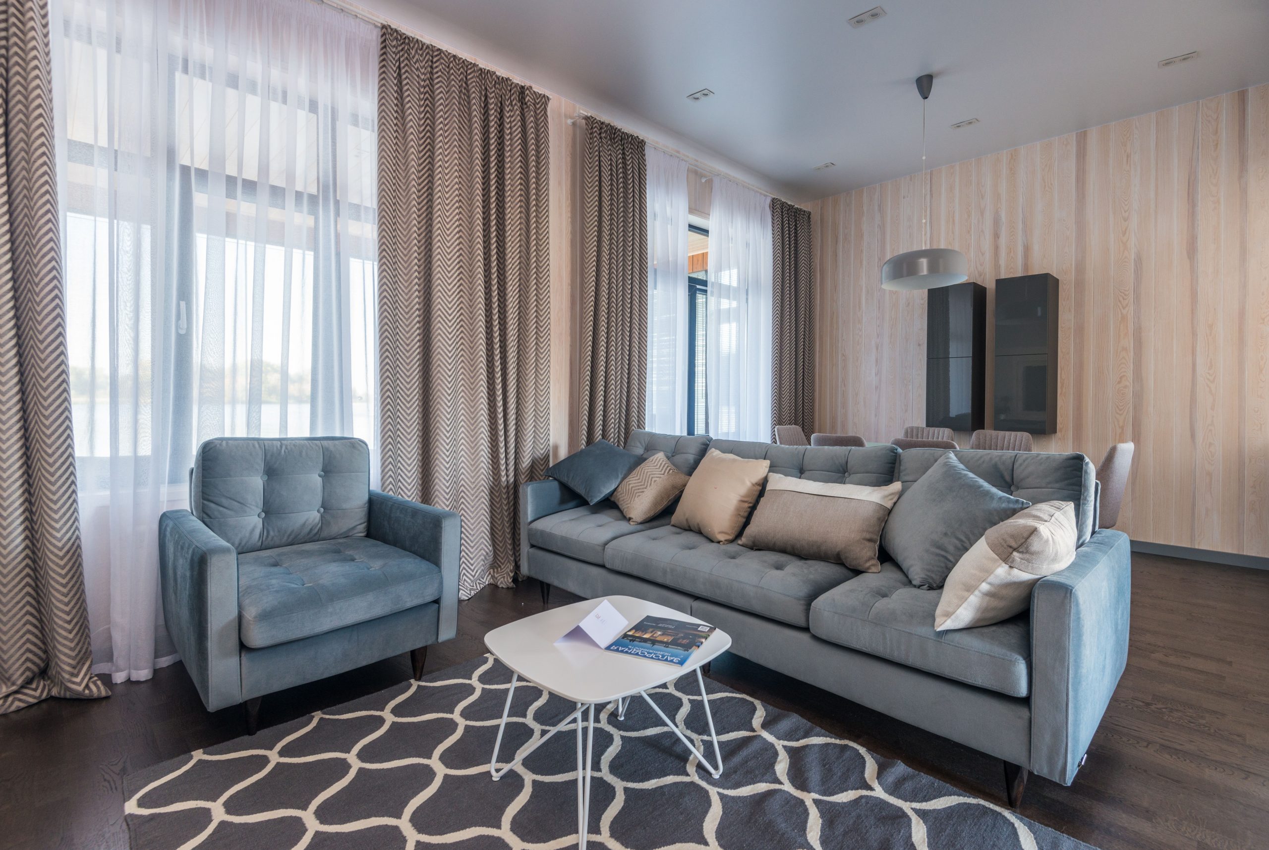 Salon avec rideaux motifs et canapé bleu