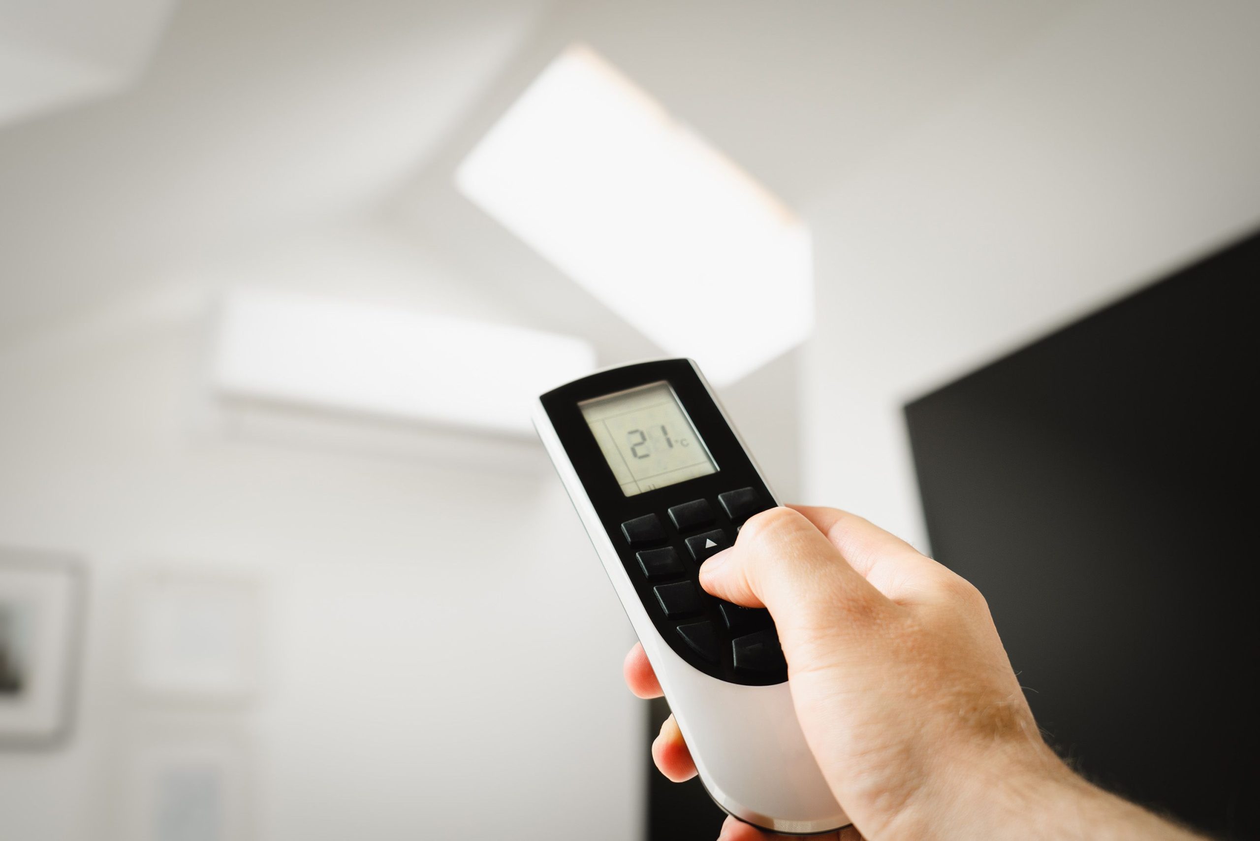 Homme contrôlant climatiseur avec télécommande